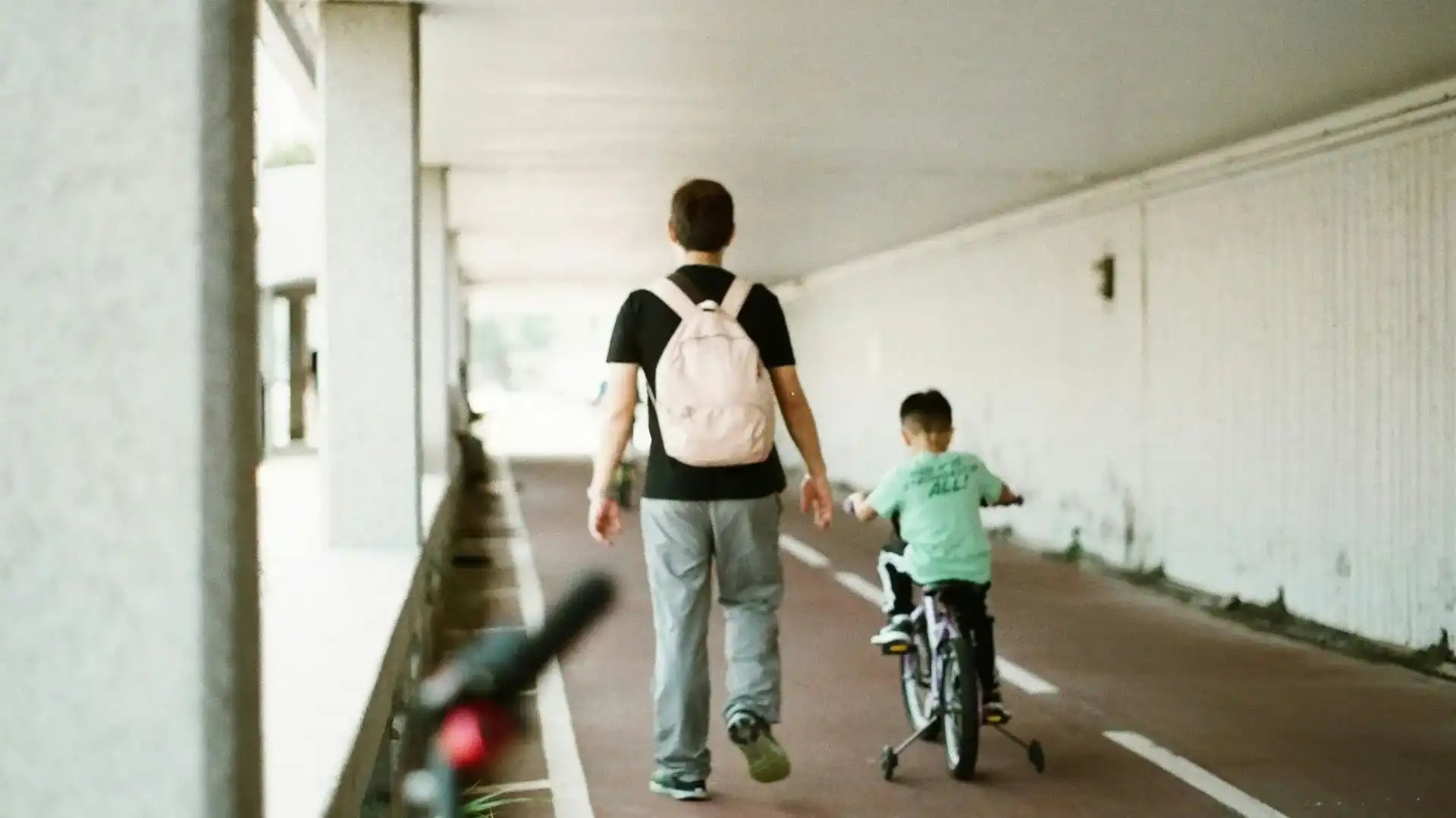 Vuxen går bredvid barn som cyklar under en gångtunnel.