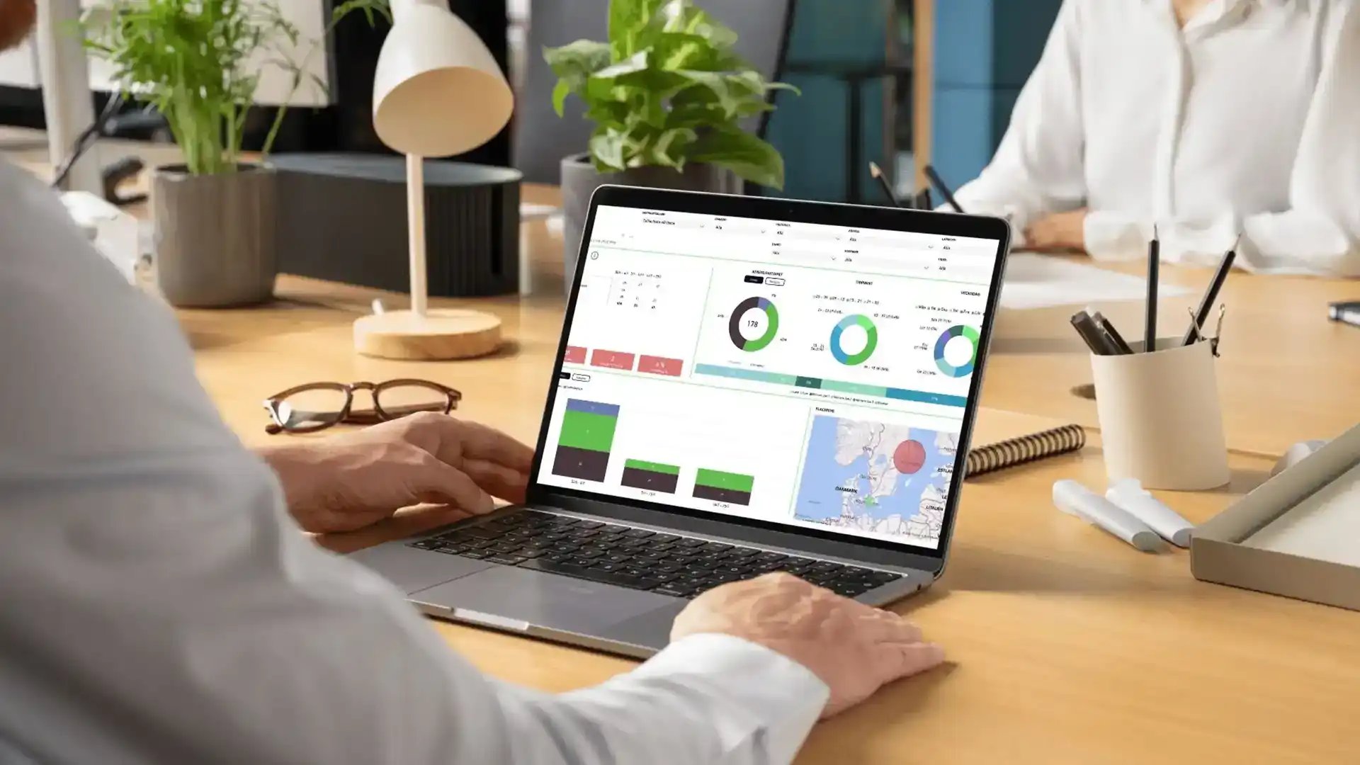 Person arbetar vid laptop med statistik och kartor på skärmen.