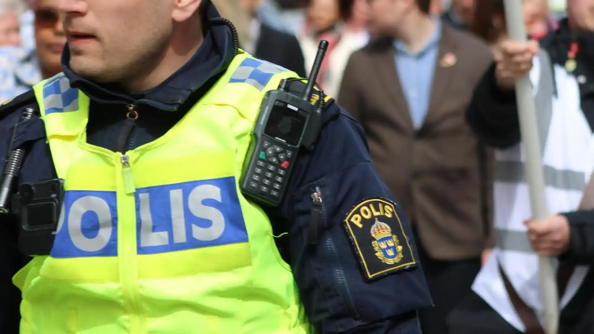 Polis i reflexväst med radio på axeln.